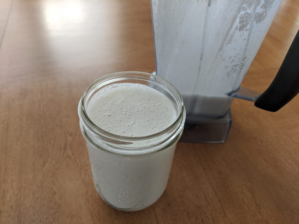 Cashew milk in pint jar next to Vitamix blender